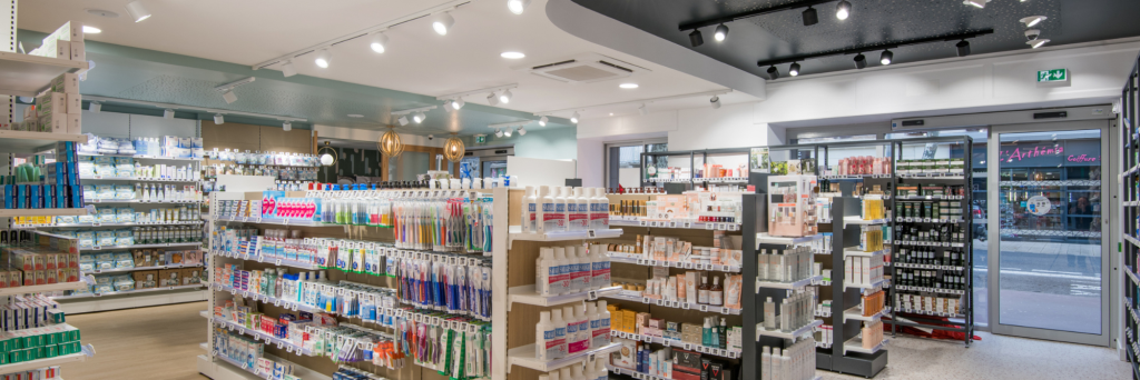 Vue d’ensemble de l’espace de vente lumineux et chaleureux de la Pharmacie Carrière, organisé par univers santé.