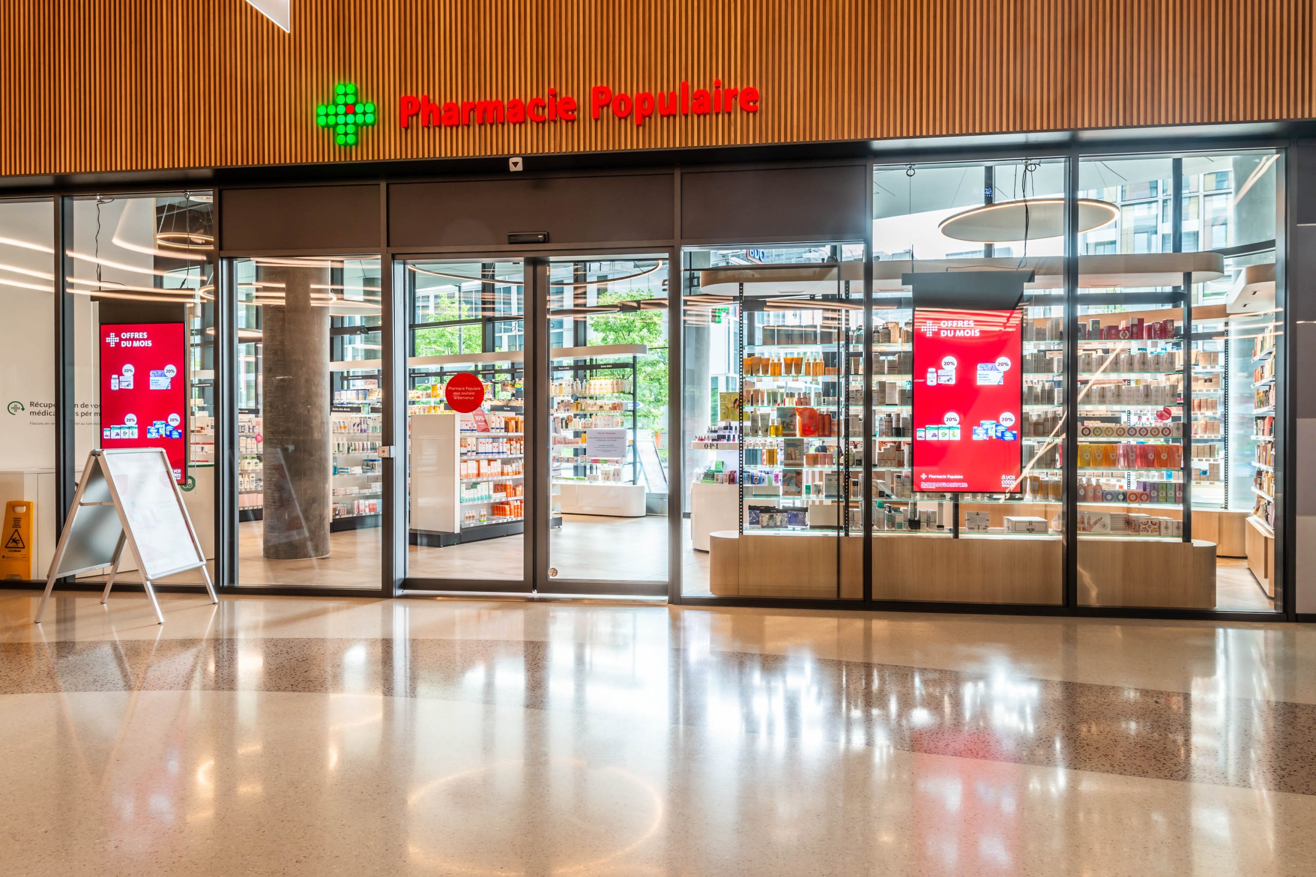 Façade depuis mall Pharmacie Populaire Etang. Transparence des linéaires en vitrine