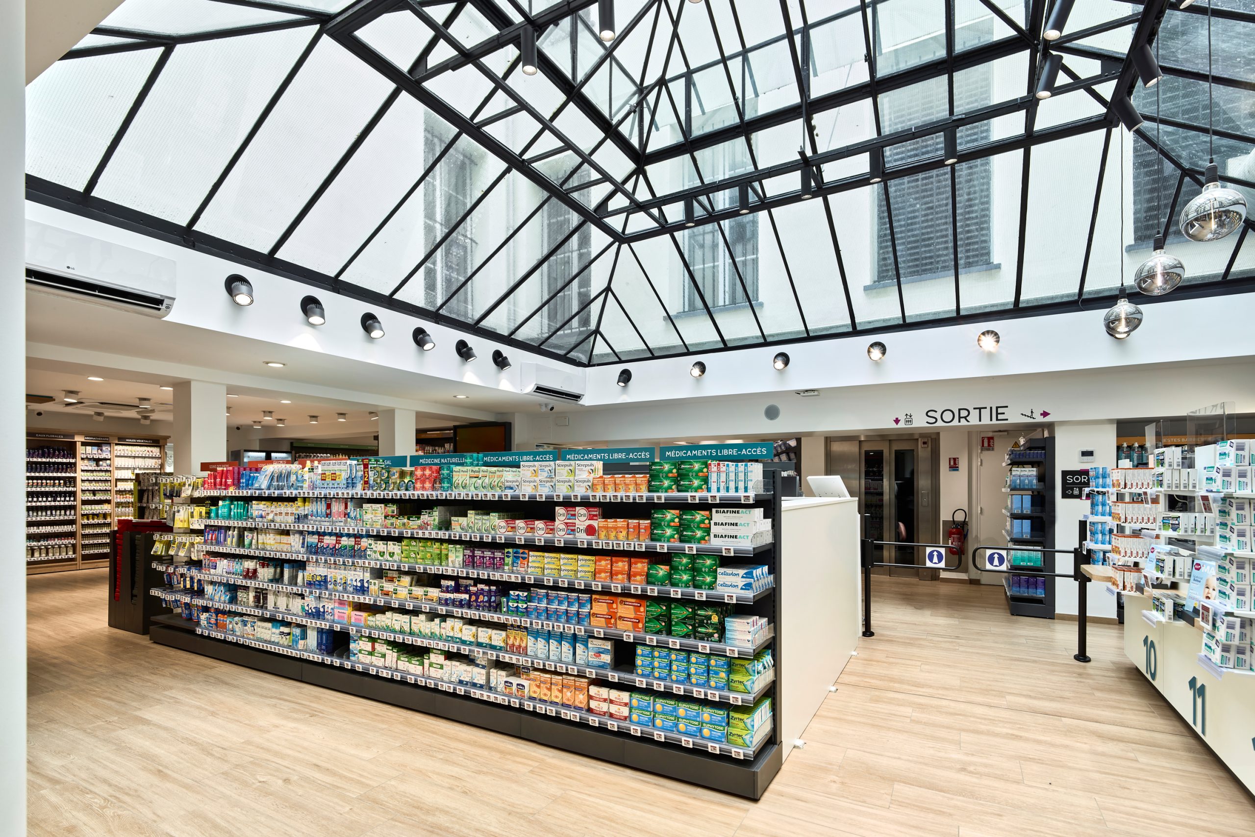 Espace de vente lumineux et moderne de la Pharmacie Carré Opéra, organisé sur deux niveaux pour un parcours client fluide.