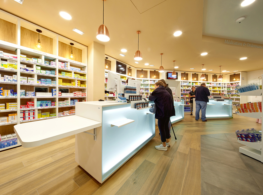 Comptoirs lumineux et espace d’accueil chaleureux — teintes douces et luminaires design favorisant la relation patient-pharmacien.