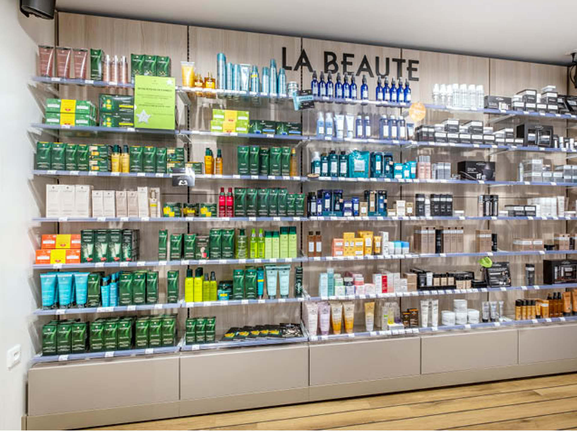 Corner beauté avec mobilier épuré et tablettes en verre mettant en valeur les produits cosmétiques, facilitant la découverte et le choix par la patientèle.