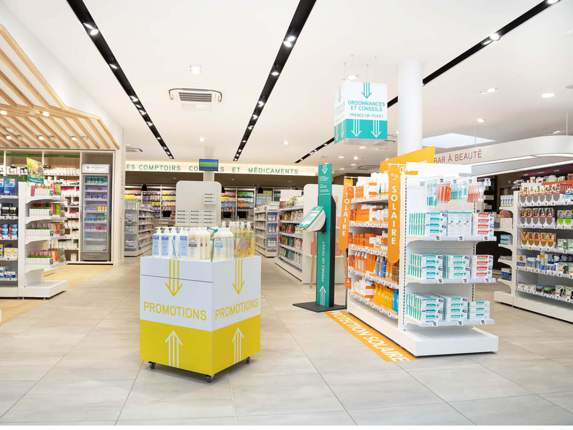 Vue d’ensemble de l’espace de vente, spacieux, lumineux et sectorisé avec des matériaux chaleureux.