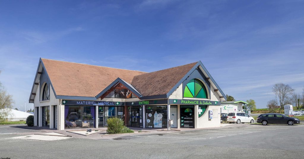 Façade de la pharmacie moderne et lumineuse, intégrée harmonieusement à l’environnement local.
