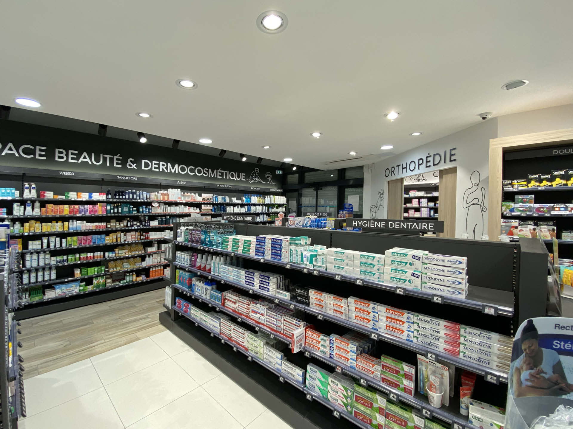 Espace de vente de la Pharmacie Escarra, vaste et lumineux, structuré par une signalétique claire et un mobilier harmonieux pour fluidifier le parcours client.