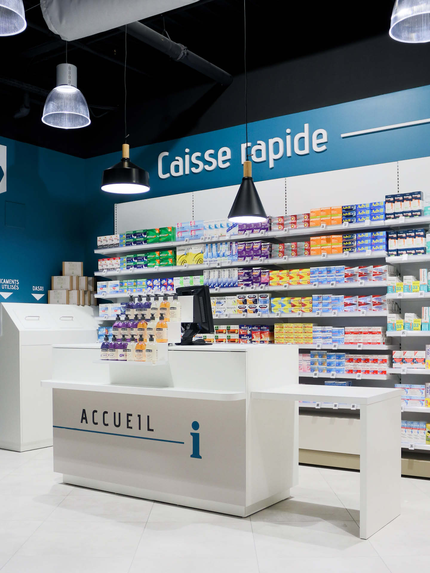Comptoirs blancs sur-mesure, accompagnés d’un plafond graphique noir et d’un jeu de lumières.