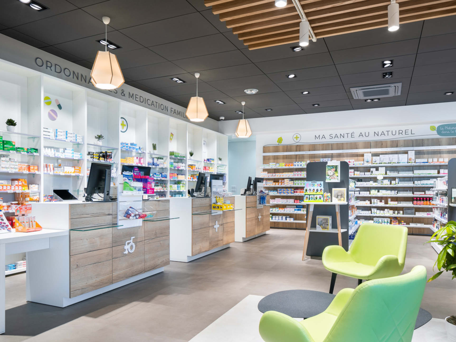 Espace comptoirs en bois aménagé avec des lustres et des éléments qui permet d'apporter de la chaleur au sein de la pharmacie.