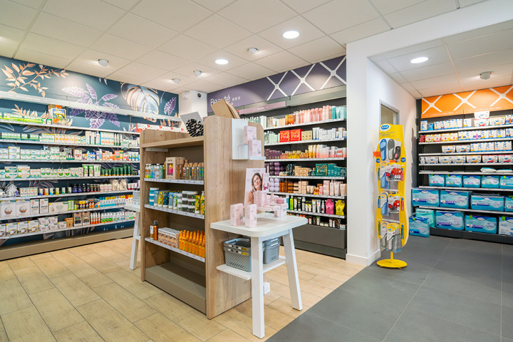Espace de vente de la pharmacie avec linéaires et têtes de gondole, mettant en valeur les produits dans un agencement soigné.