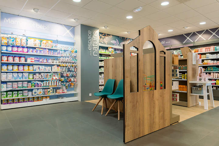 Espace d’attente de la pharmacie, avec un coin enfant intégré à un élément en bois fait sur mesure dans l’agencement global.
