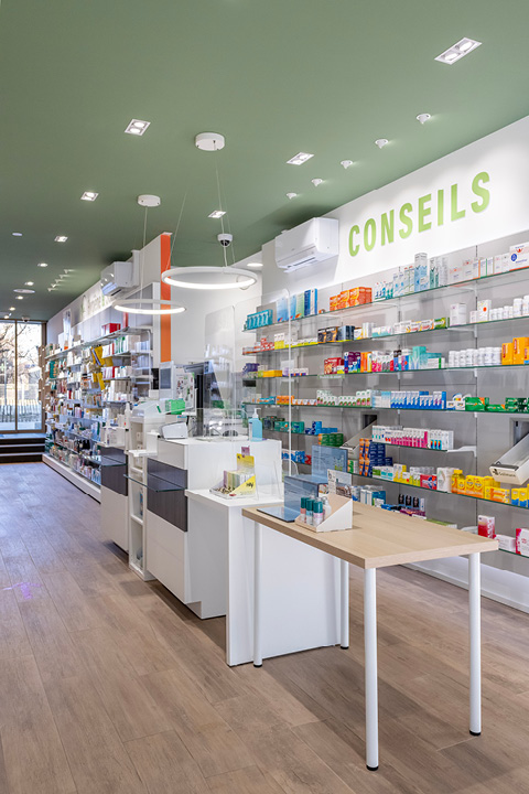 Comptoir épuré en bois et verre à la Pharmacie Gare Chêne-Bourg, conçu pour favoriser la proximité et le conseil patient.