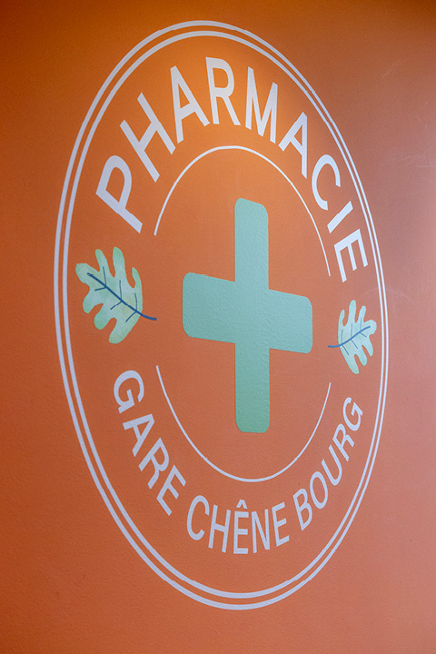 Signalétique claire et cohérente dans la Pharmacie Gare Chêne-Bourg, avec icônes personnalisées inspirées du logo pour identifier les différents espaces santé.