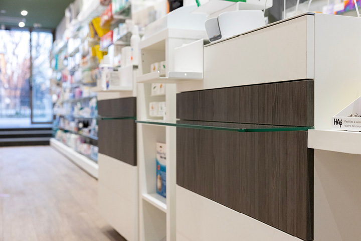 Comptoir épuré en bois et verre à la Pharmacie Gare Chêne-Bourg, conçu pour favoriser la proximité et le conseil patient.