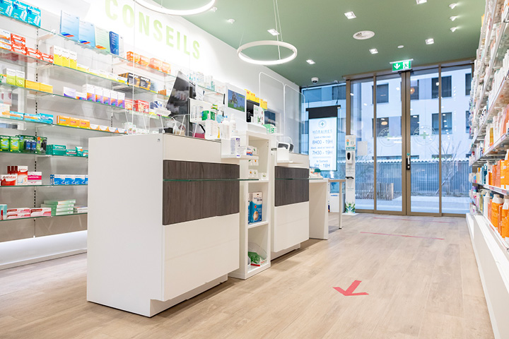 Comptoir épuré en bois et verre à la Pharmacie Gare Chêne-Bourg, conçu pour favoriser la proximité et le conseil patient.