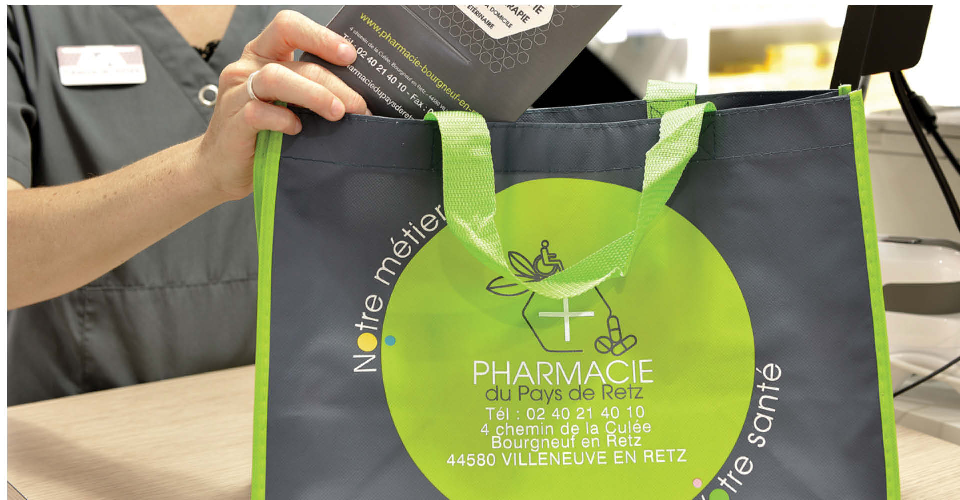 Focus sur le design graphique de la pharmacie du Pays de Retz : sac au logo, badges et supports de communication harmonisés, reflétant une identité forte et cohérente.
