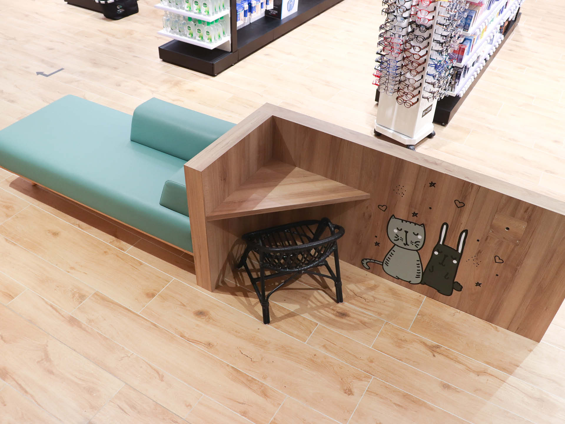 Espace d’attente avec un coin enfant intégré dans l’aménagement de la pharmacie, agrémenté d’éléments graphiques ludiques pour rappeler cet univers et créer une ambiance conviviale et familiale.