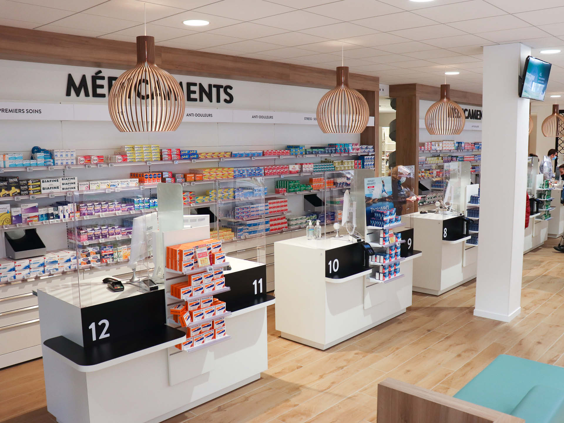 Espace comptoir bien délimité grâce à un jeu de lumières mettant en valeur cette zone centrale dans l’aménagement de la pharmacie, pour renforcer la visibilité et la convivialité de l’espace.