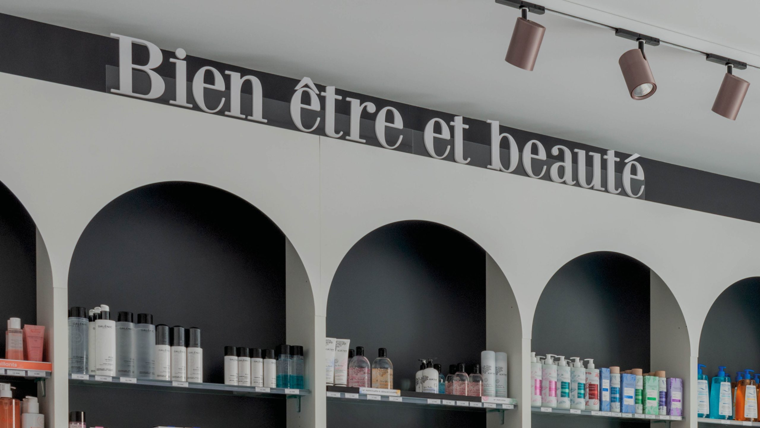 Gros plan sur la signalétique intérieure claire et harmonisée, guidant les clients dans l’officine.