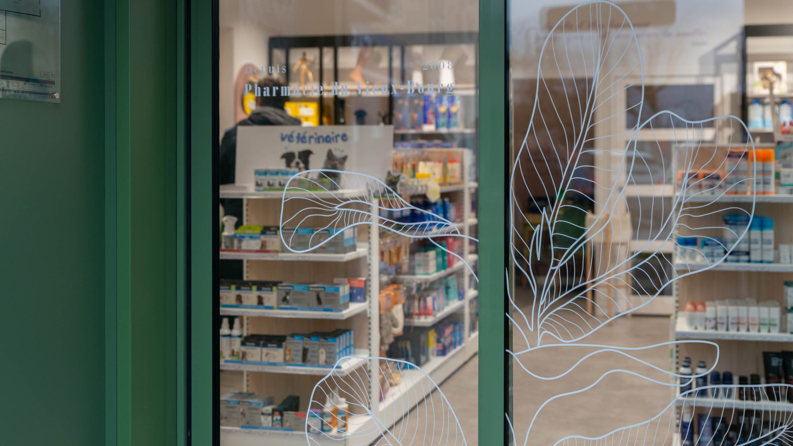 Gros plan sur les éléments graphiques et typographiques de l’identité visuelle, appliqués de manière cohérente dans la pharmacie.