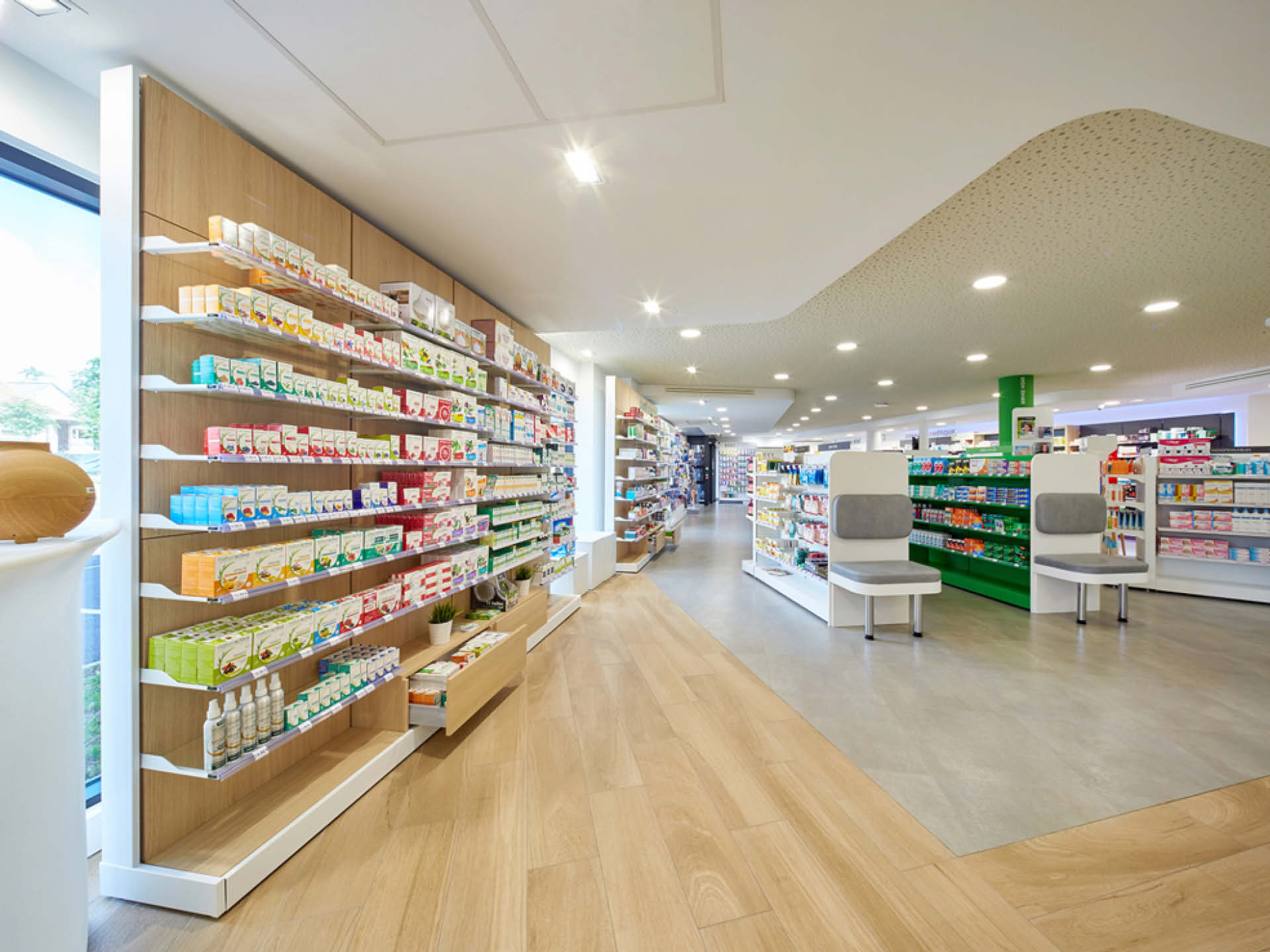 Espace de ventes avec mise en valeur du plafond de la pharmacie via un travail de matière au sein de l'agencement.