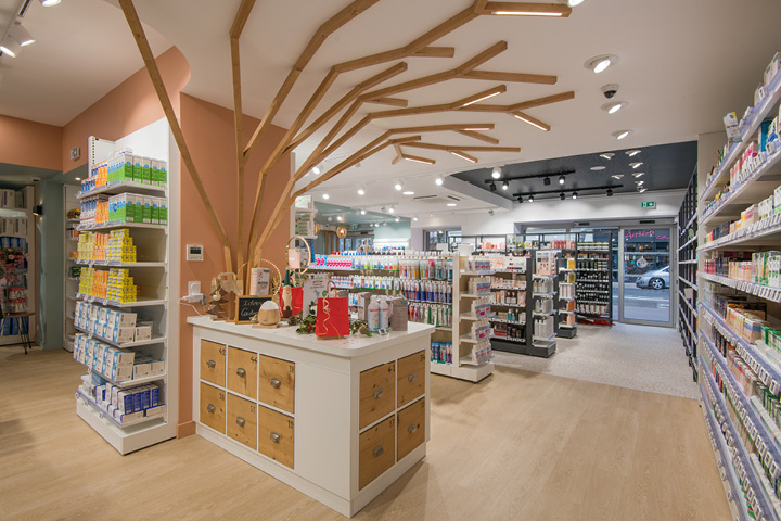 Arbre en bois central illuminé, symbole de l’identité naturelle de la pharmacie, représentant la sève et la vitalité.