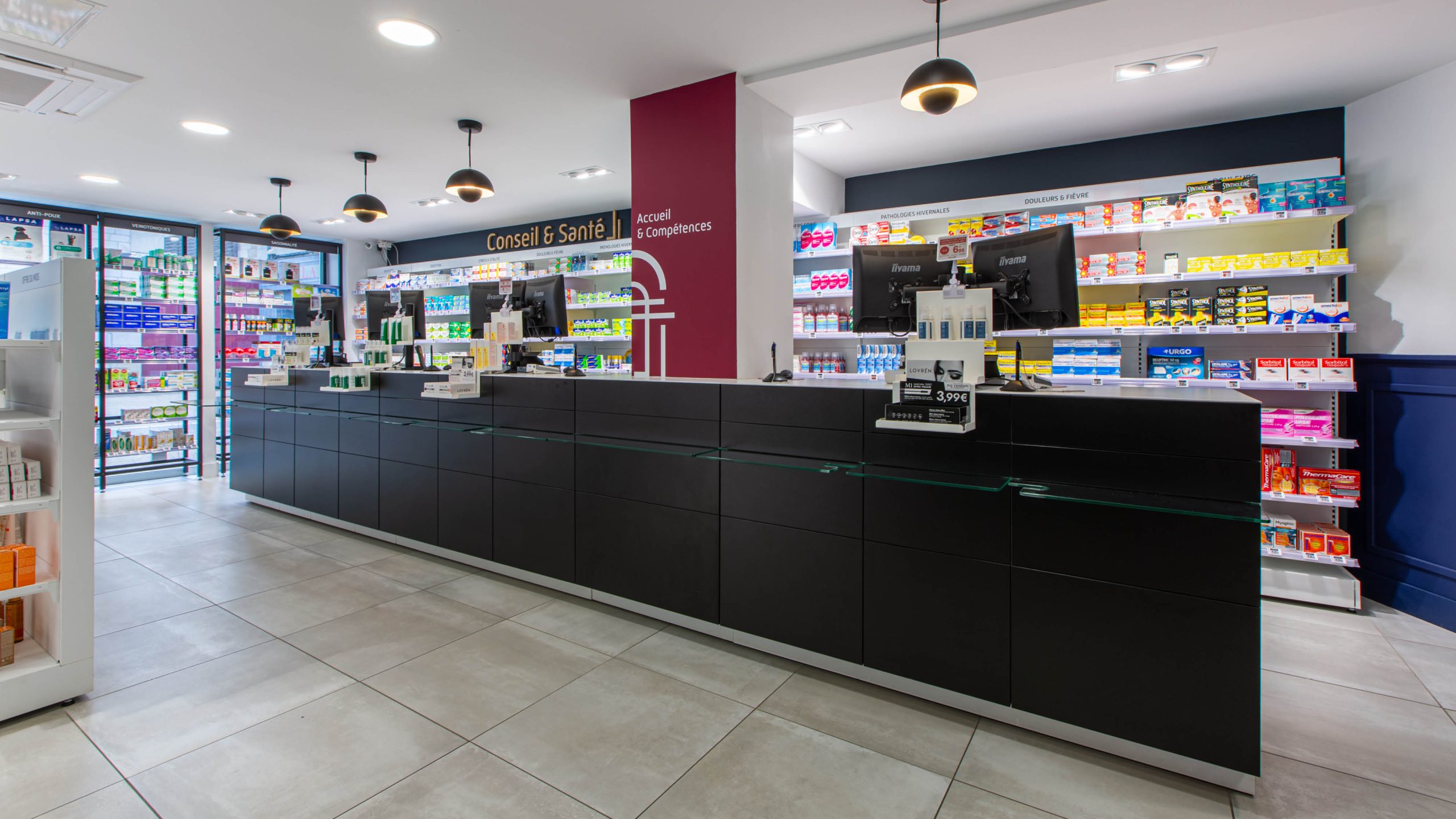 Comptoirs noirs et lustres industriels dans un espace d’attente confortable et chaleureux.