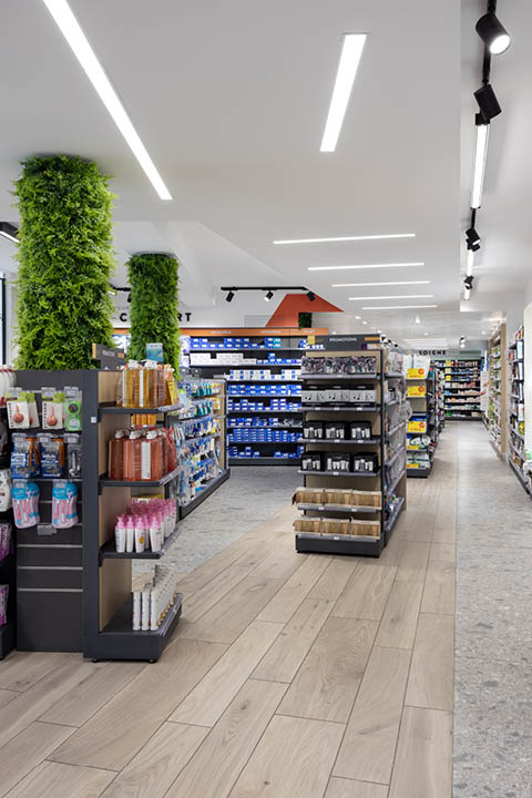 Espace de vente avec lames en bois et bandes LED au sol guidant le parcours client vers les comptoirs.