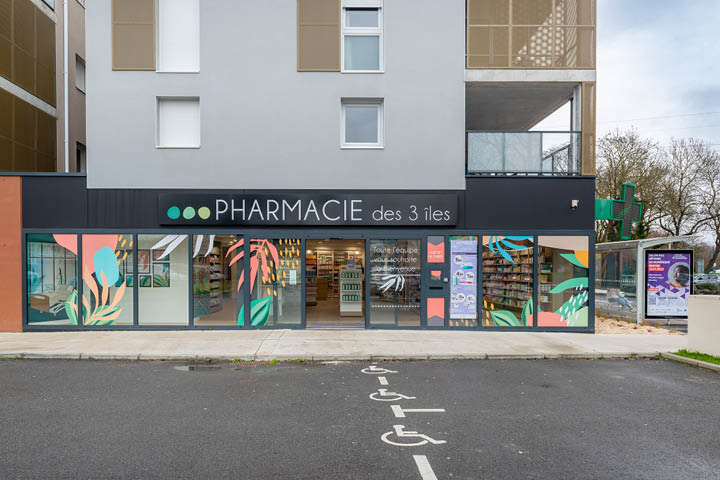 Façade de la Pharmacie des 3 Îles à Indre, mise en valeur par une vitrophanie graphique colorée inspirée des îles de Loire et de la faune locale.