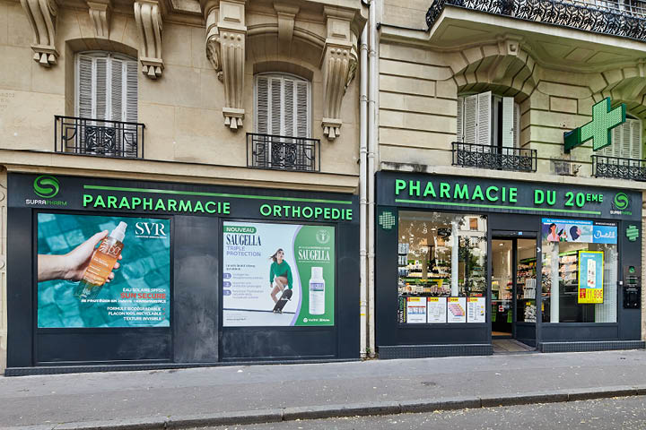 Façade moderne et accueillante de la Pharmacie du 20ᵉ à Paris avec signalétique Suprapharm et grandes vitrines transparentes.