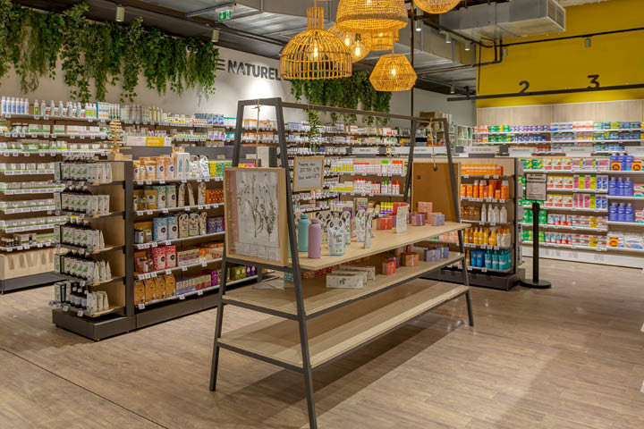 Corner santé naturelle avec linéaires THOR en bois, végétalisation murale et luminaires en fibres naturelles.