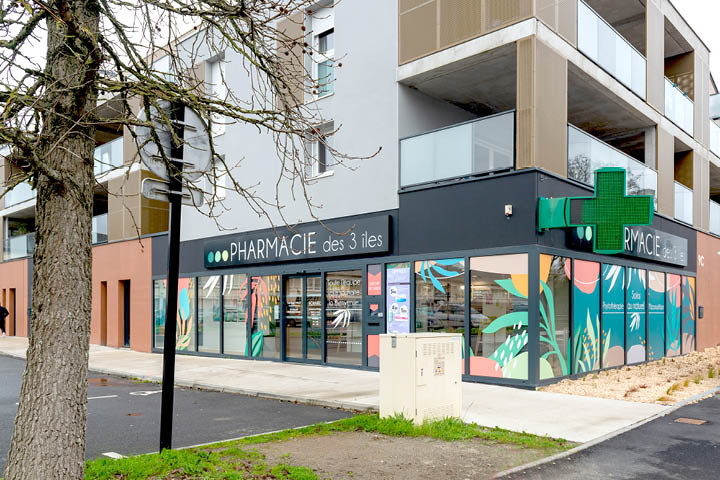 Façade de la Pharmacie des 3 Îles à Indre, mise en valeur par une vitrophanie graphique colorée inspirée des îles de Loire et de la faune locale.