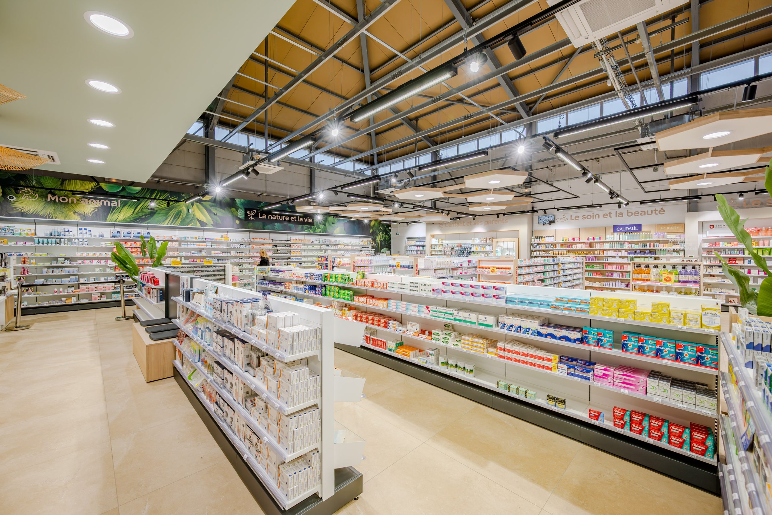 Vue globale de la Grande Pharmacie avec plafond en nid d'abeille et matériaux nobles comme le bois.