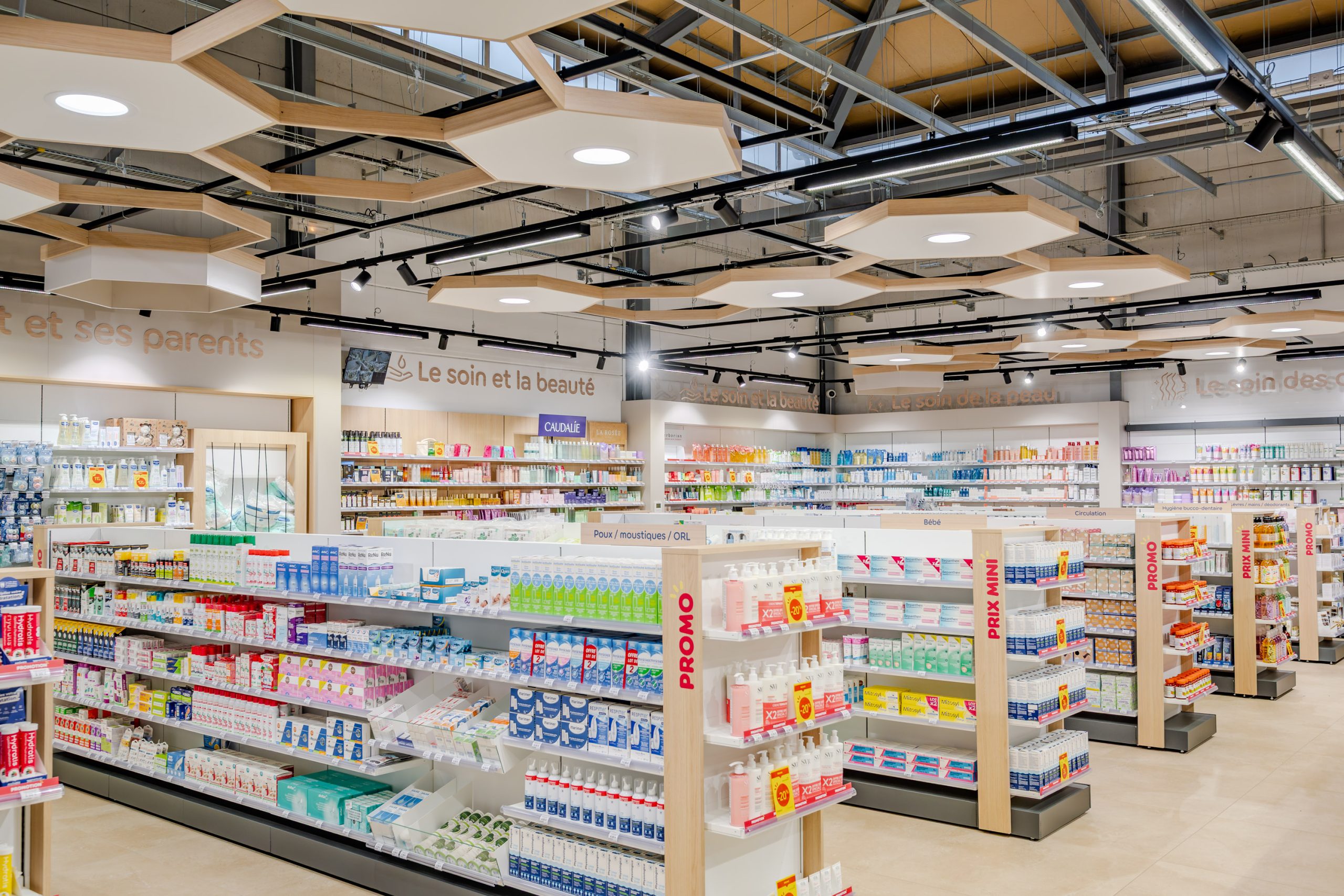 Vue globale de la Grande Pharmacie avec plafond en nid d'abeille et matériaux nobles comme le bois.