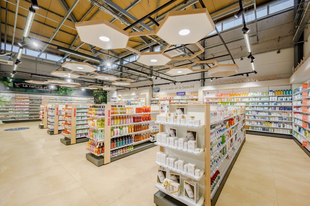 Vue globale de la Grande Pharmacie avec plafond en nid d'abeille et matériaux nobles comme le bois.