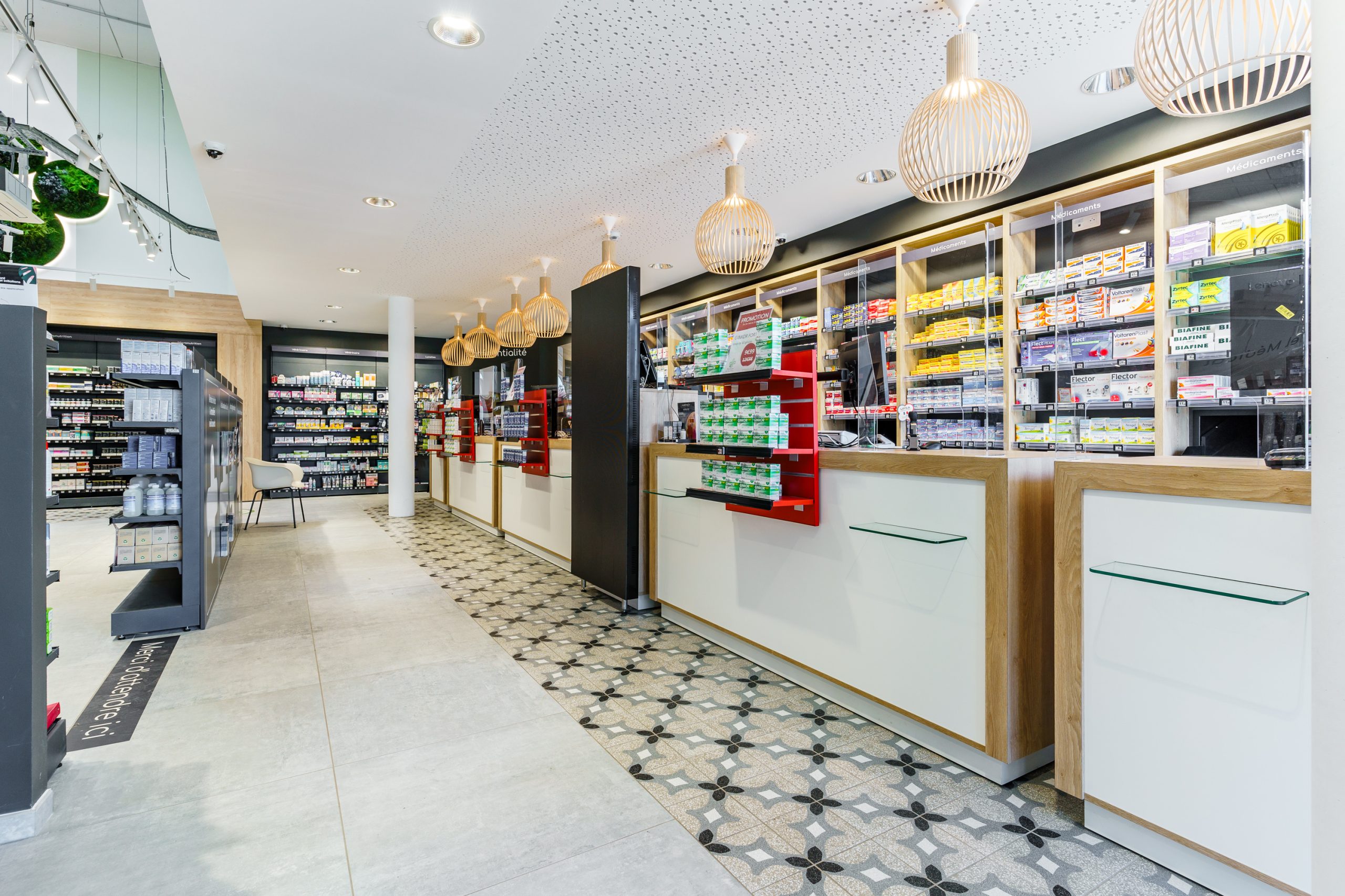 Espace comptoir, luminaires et file d'attente dans la pharmacie du Pays Haut.