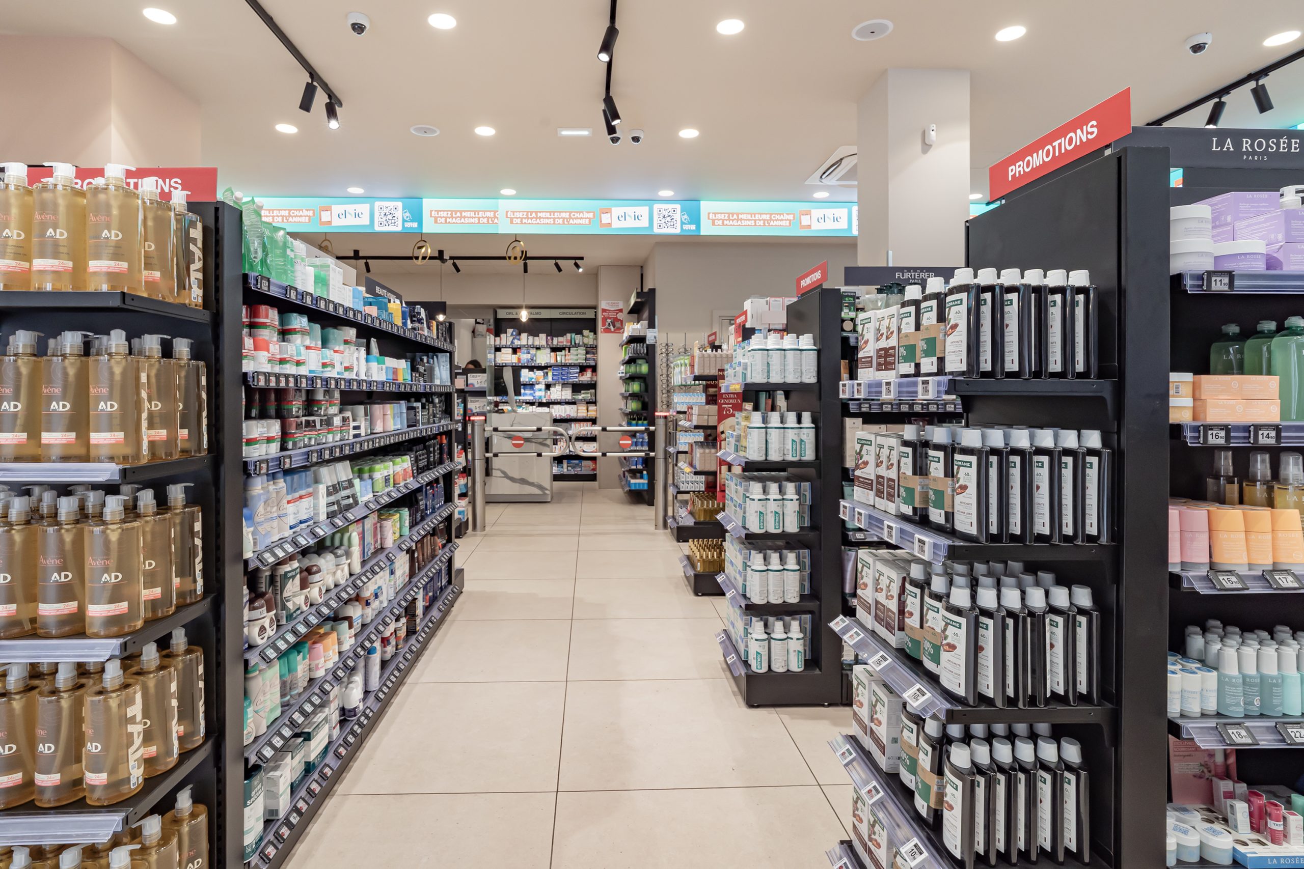 Allées de parapharmacie de la Pharmacie du Dôme avec rayons soins du corps, capillaires et promotions.