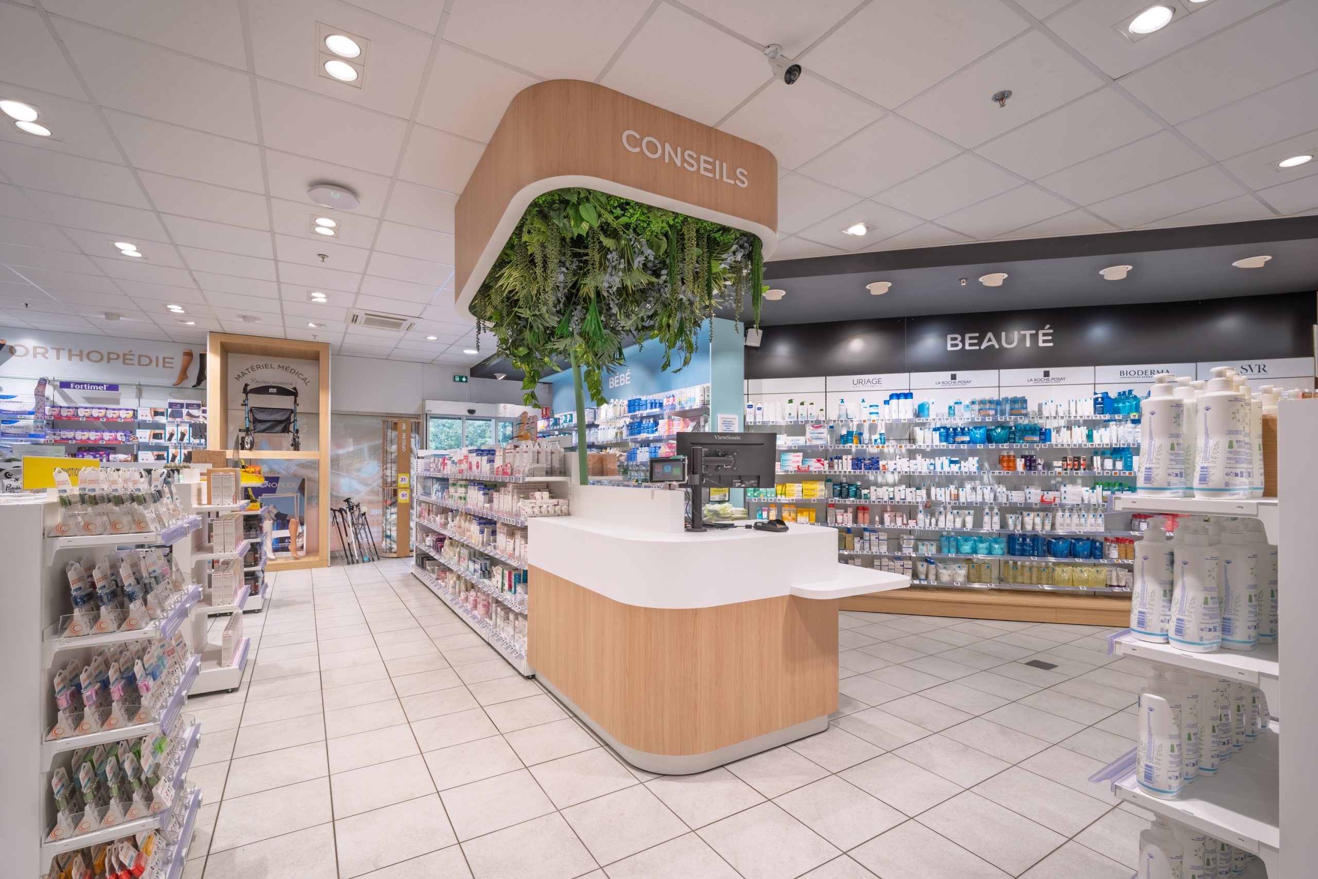 Espace conseil et comptoir d'accueil de la Pharmacie du Lac avec ambiance végétale.