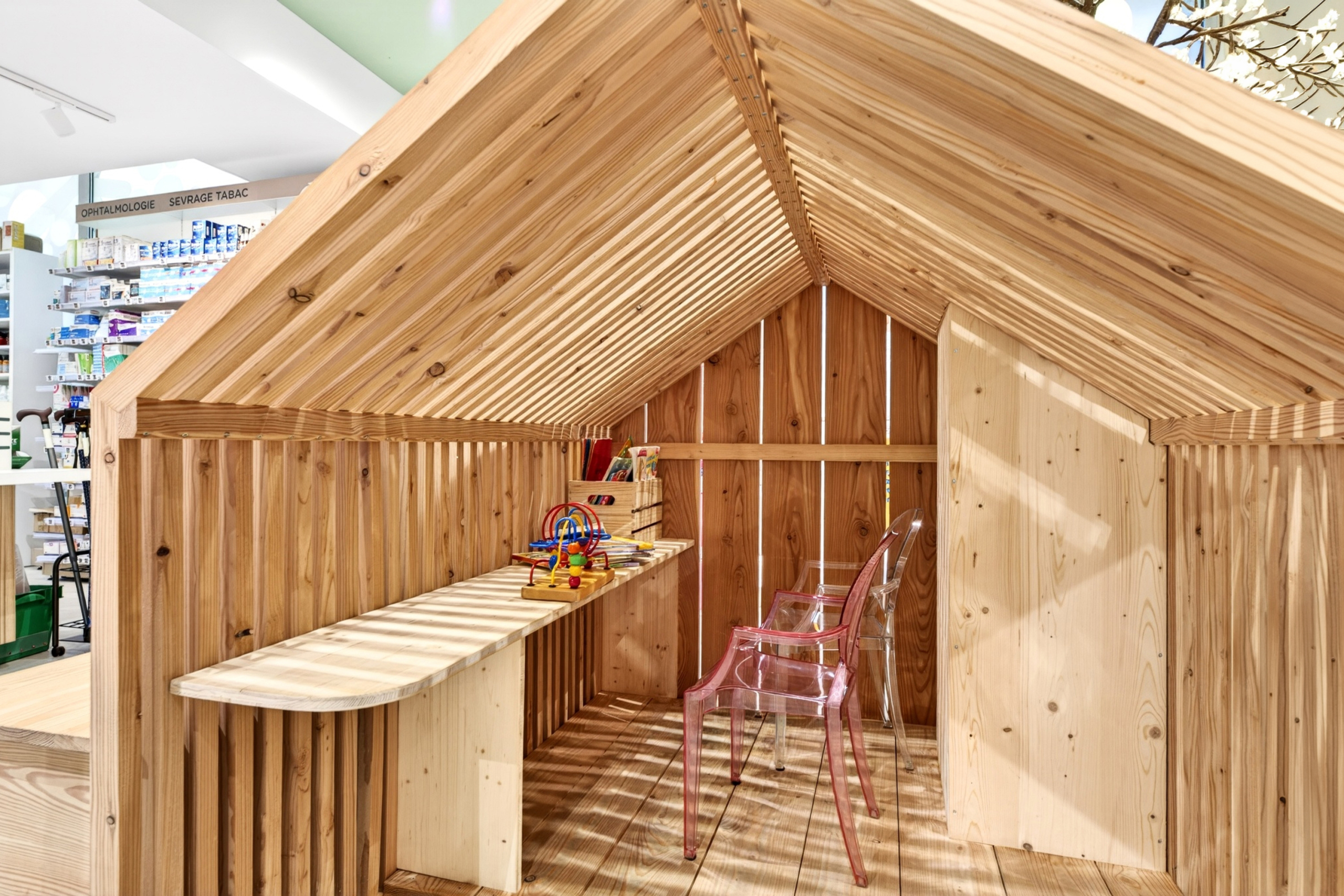 Espace enfants en cabane bois de la Pharmacie Les Garennes pour un accueil ludique des familles.