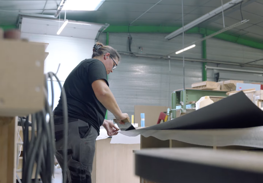 Menuisier réalisant le placage manuel et les finitions d'un meuble dans l'atelier Mobil M Agencement.