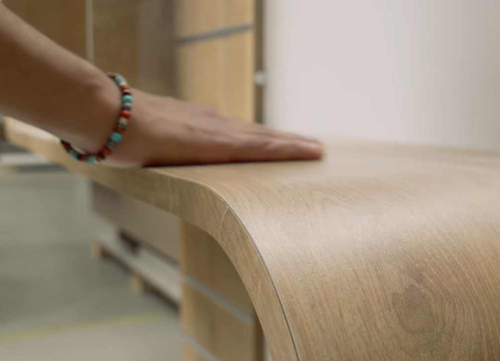 Main posée sur la finition d'un comptoir en bois cintré conçu sur mesure par Mobil M Agencement