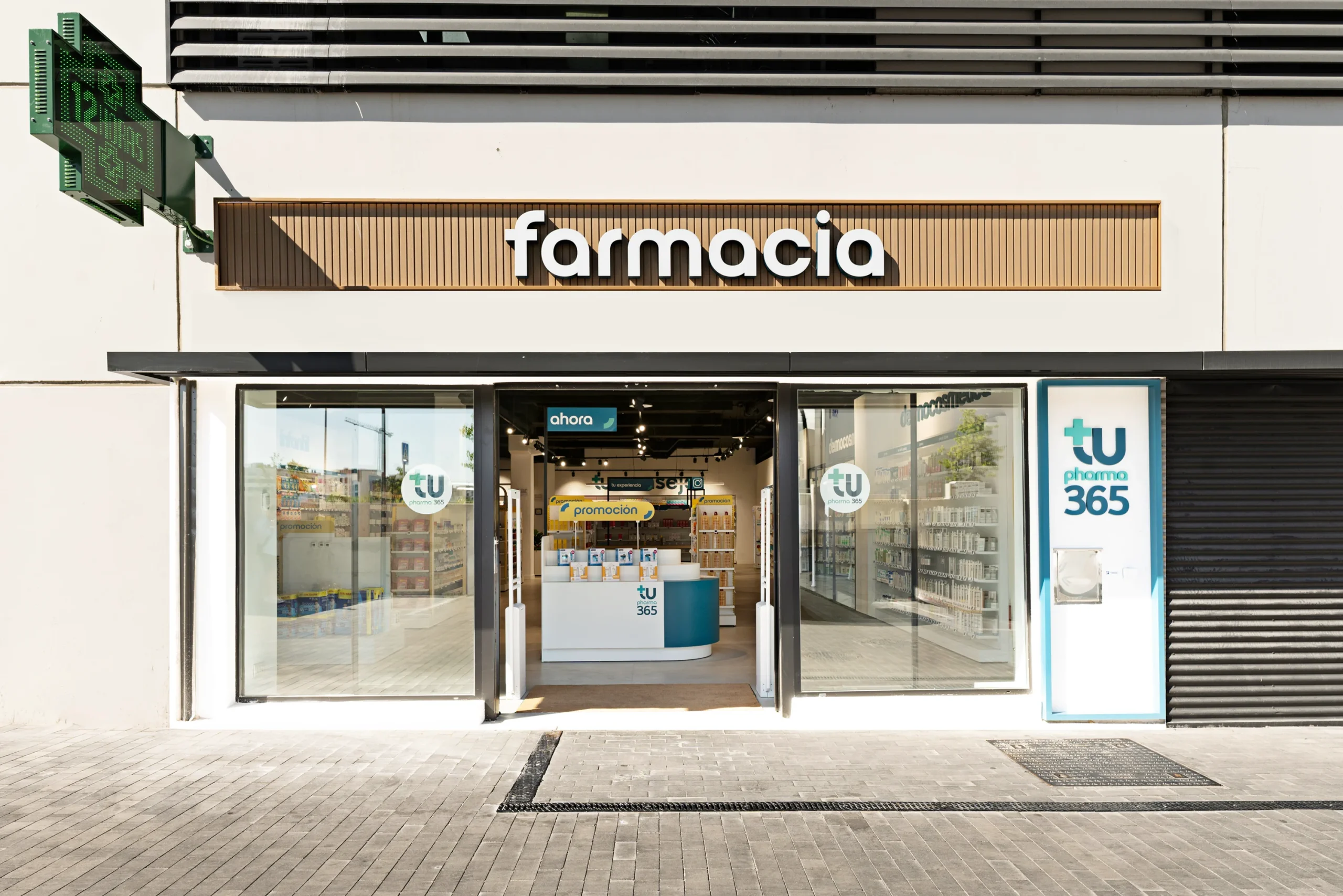 Fachada de la farmacia Mayorazgo con franja superior en madera, rotulación exterior y grandes ventanales.