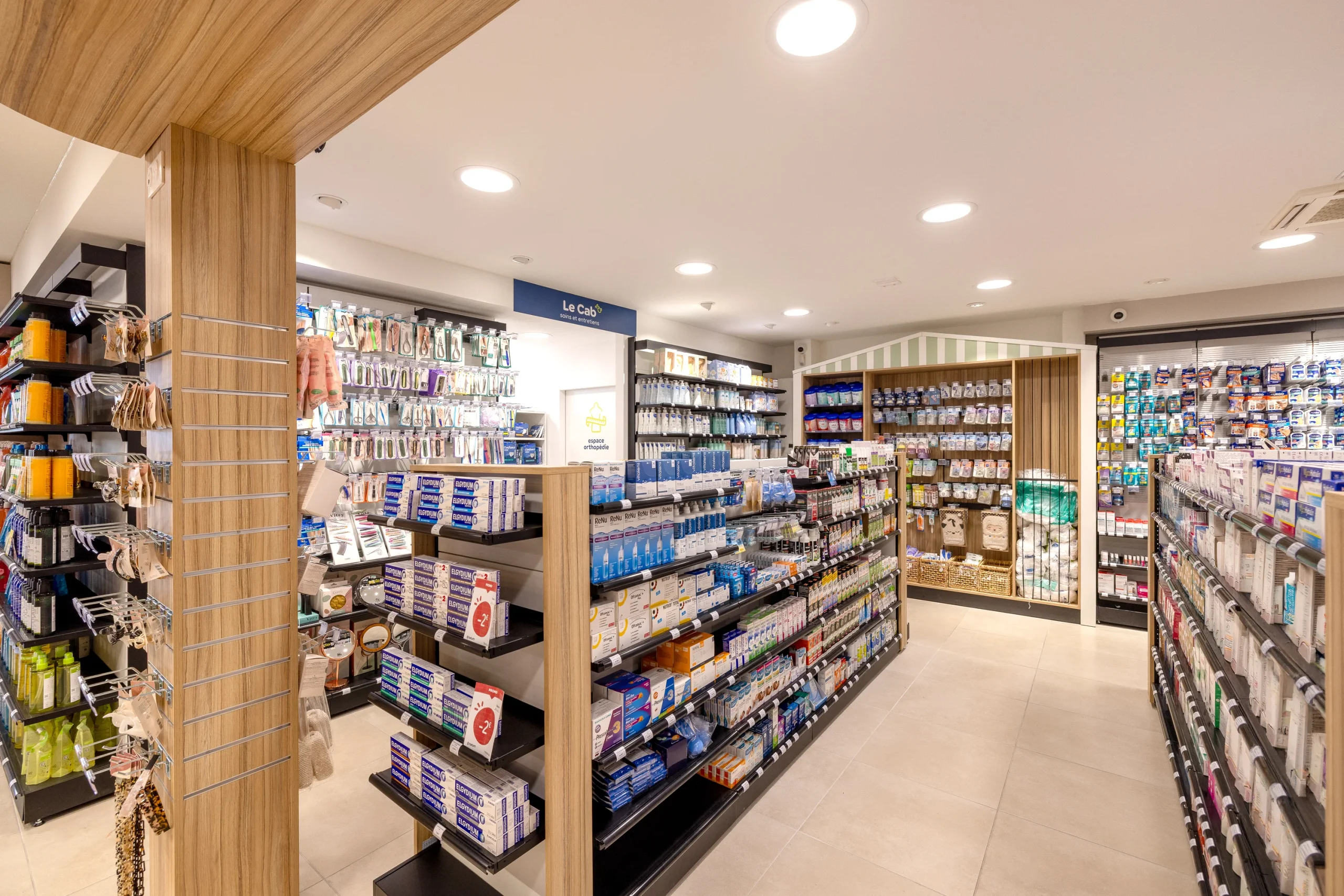 Allée de la Pharmacie du Golfe bordée de gondoles, avec poteau et poutre habillés de bois.