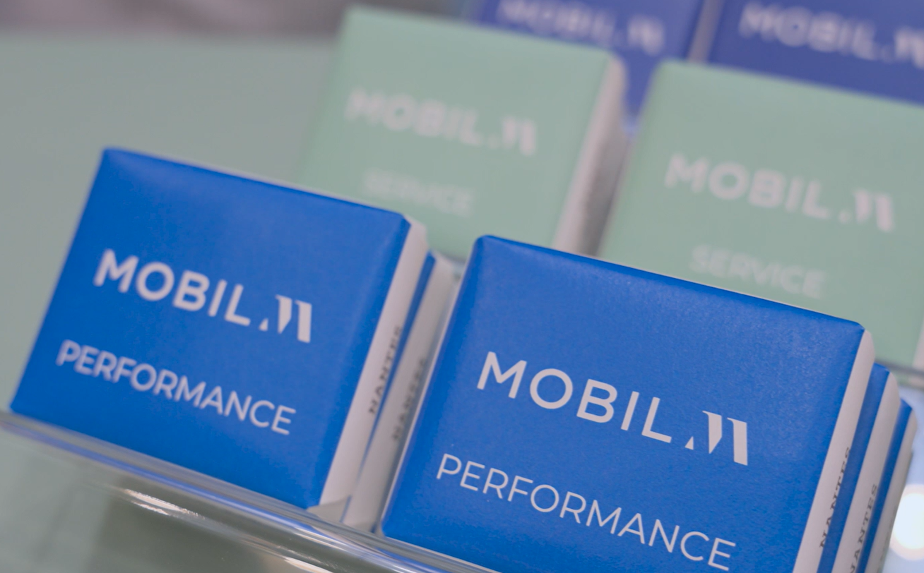 P'tits Beurres Vincent Guerlais sur un présentoir et de couleurs bleues et vertes avec logos blancs 'Mobil M' et textes "Performance" et "Service" et "Design".